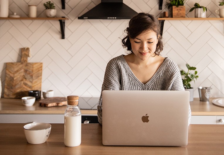 Smiling woman using laptop in kitchen