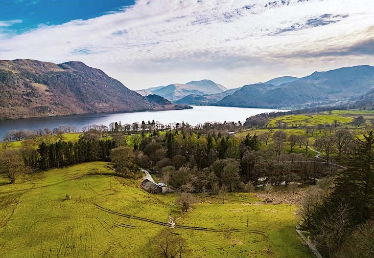 An aerial view of a lake surrounded by mountains in the Lake District
