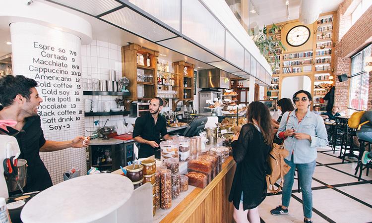 Woman standing on a food counter in a busy cafe