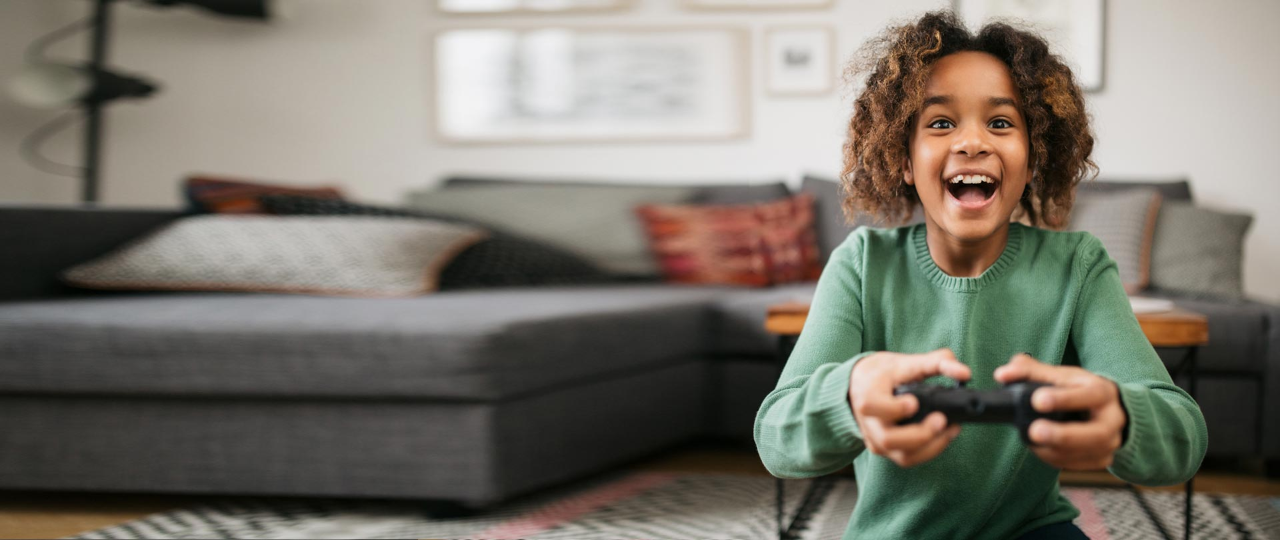 Front view of a little girl smiling and playing video games at home