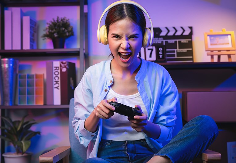 Excited young woman playing online game with headsets.