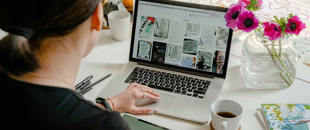 A person using laptop for graphic designs on a table with a cup of coffee