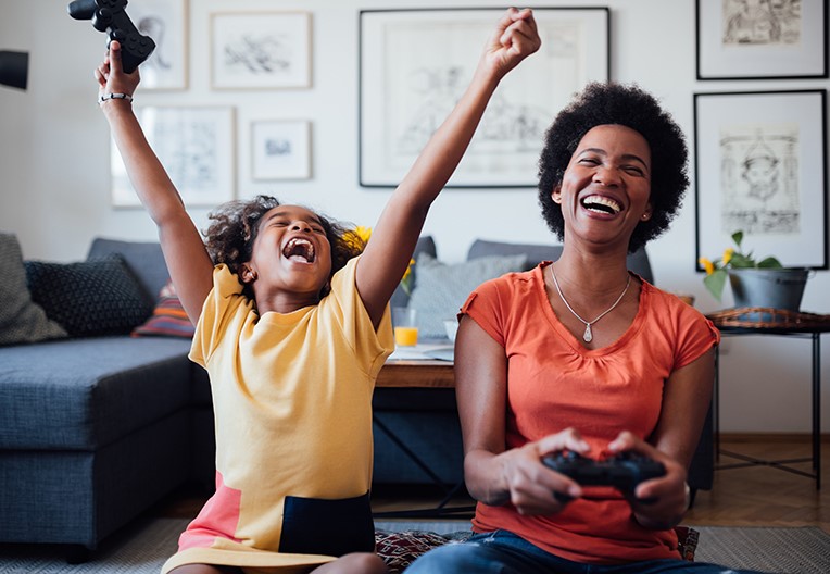 Mother playing video games with her young daughter at home