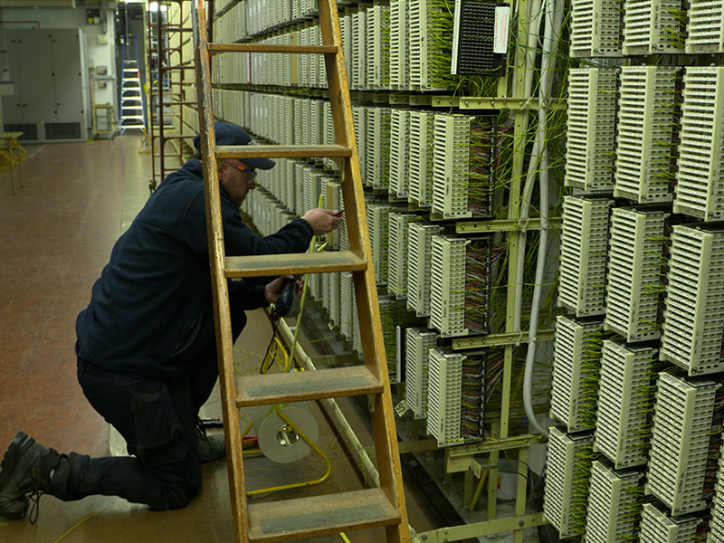  Engineer working inside an Openreach telephone exchange on copper broadband network infrastructure