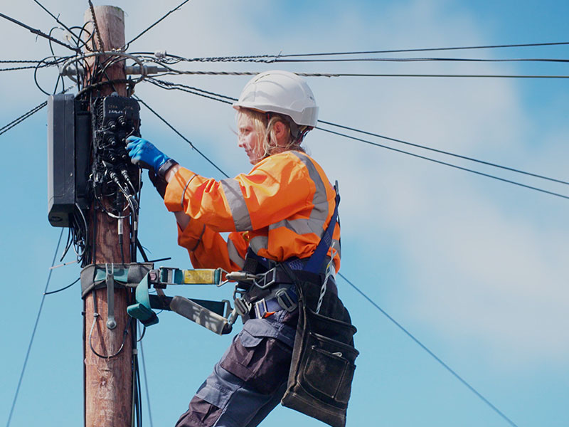 Engineer installing Full Fibre broadband cables on a telegraph pole