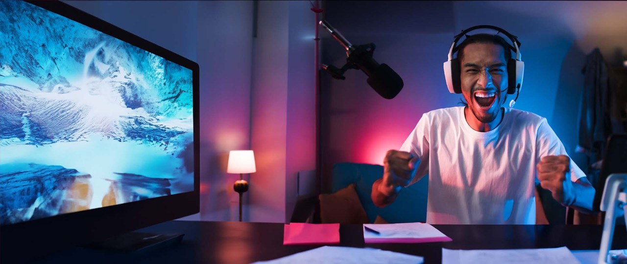 Happy young man playing online computer video game with headsets