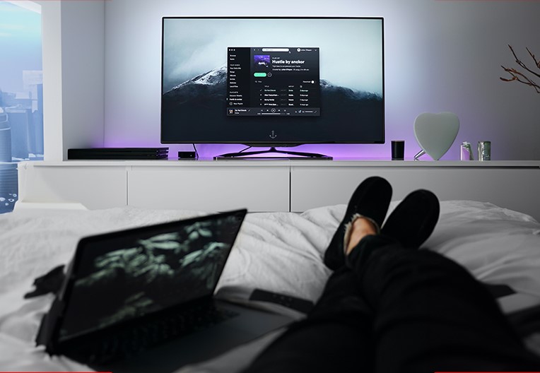 A person watching TV whilst laying down on the bed in the bedroom