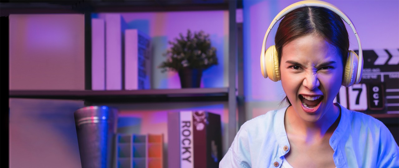 Excited young woman playing online game with headsets.