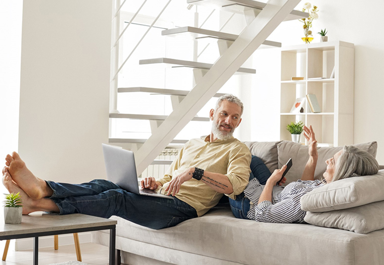 Couple sat on sofa using their personal devices