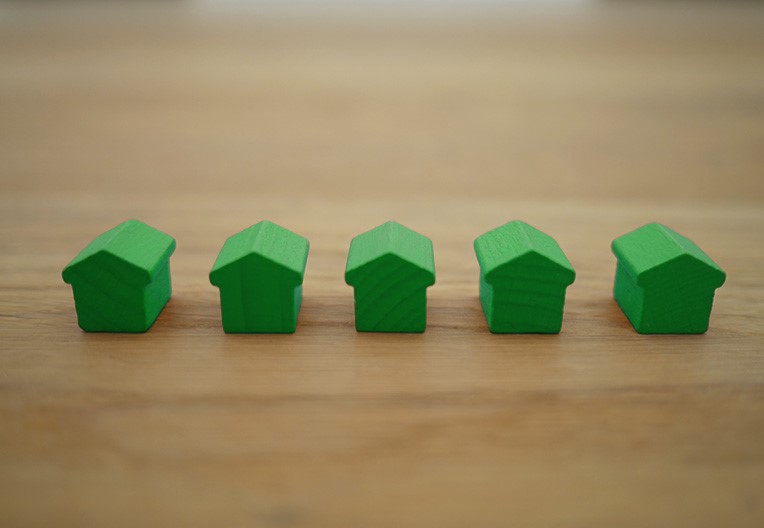 Five green house blocks on a wooden table