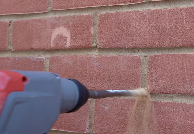 Engineer drilling into wall