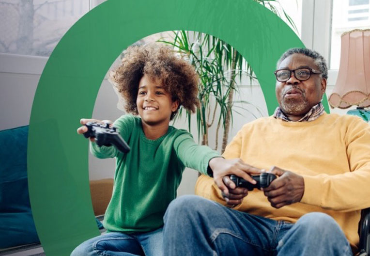 Man and young boy holding console controllers and playing video games