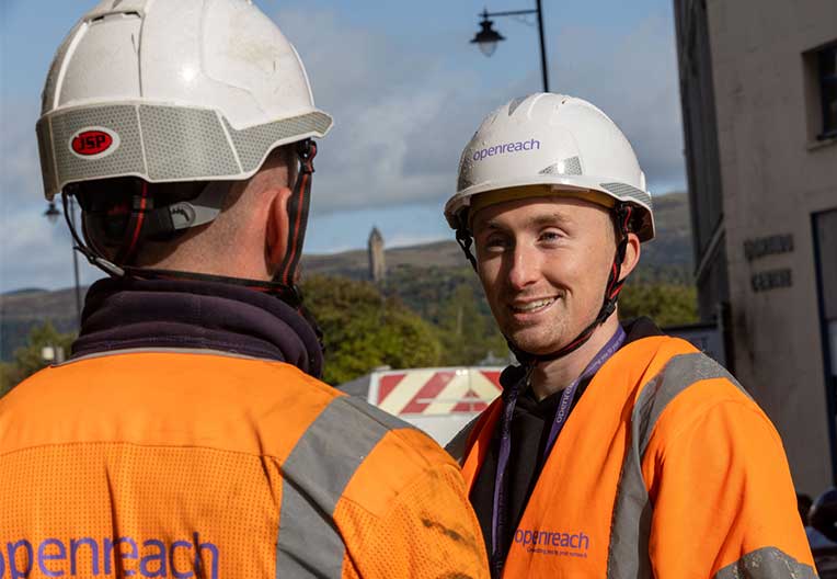 Two Openreach male engineers smiling at each other